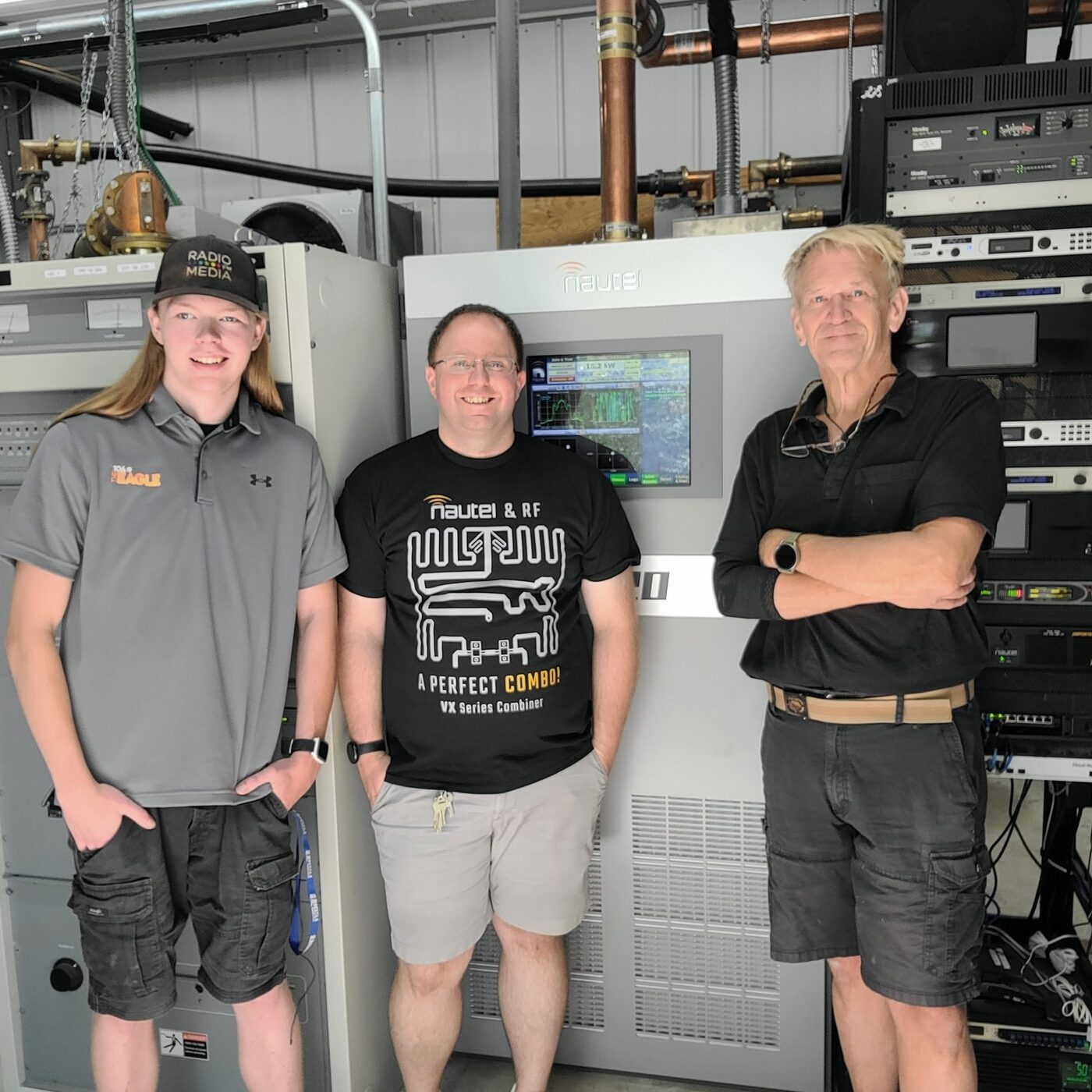 Jake with two colleagues in front of a Nautel transmitter