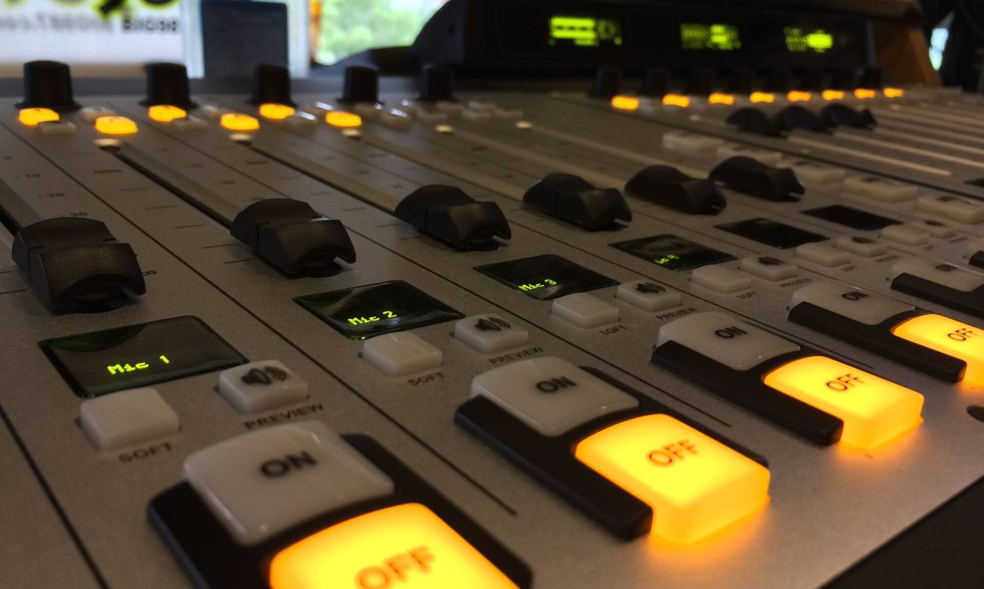 Close-up of an on-air mixing console with glowing mic buttons